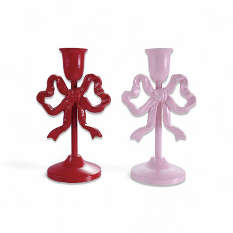 Two cast iron taper candle holders with bow design, red and pink