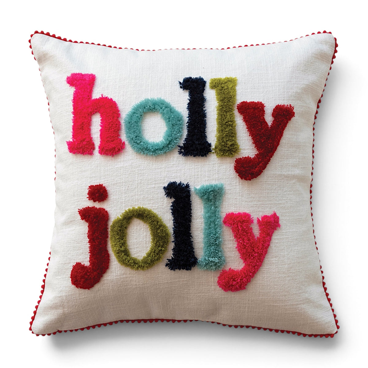 Ivory square cotton slub pillow with multicolor tufted holly jolly lettering and red pom pom trim.