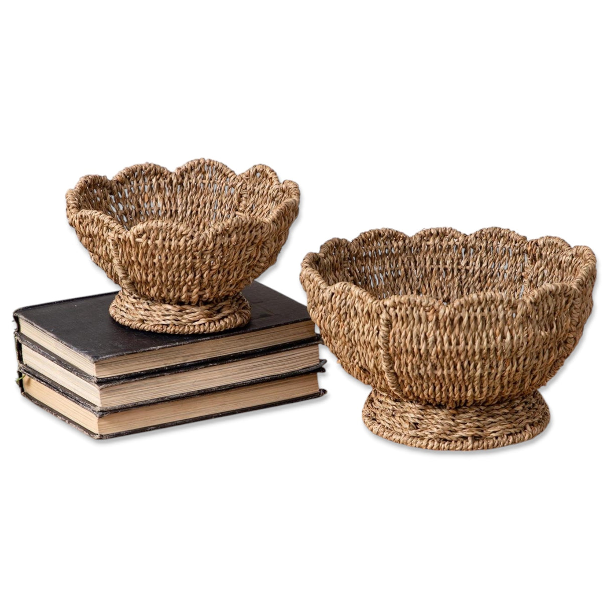 Set of two scalloped edge seagrass bowls with pedestal bases in natural woven finish.