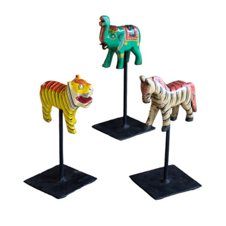 distressed wooden circus animals on stands. Zebra, elephant, and tiger.