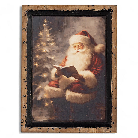 Framed artwork of Santa Claus reading a book next to a Christmas tree.