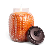 Autumn Orchards candle with orange wax in a textured glass pumpkin jar topped with a dark pumpkin-stem lid.