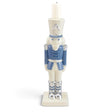 Blue and white ceramic nutcracker candleholder with silver-tone boots and accents, a square base, and a white candle atop its hat