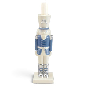 Blue and white ceramic nutcracker candleholder with silver-tone boots and accents, a square base, and a white candle atop its hat