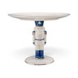 White ceramic pedestal with a blue and white nutcracker supporting a round tray, detailed with silver accents and a silver-edged base