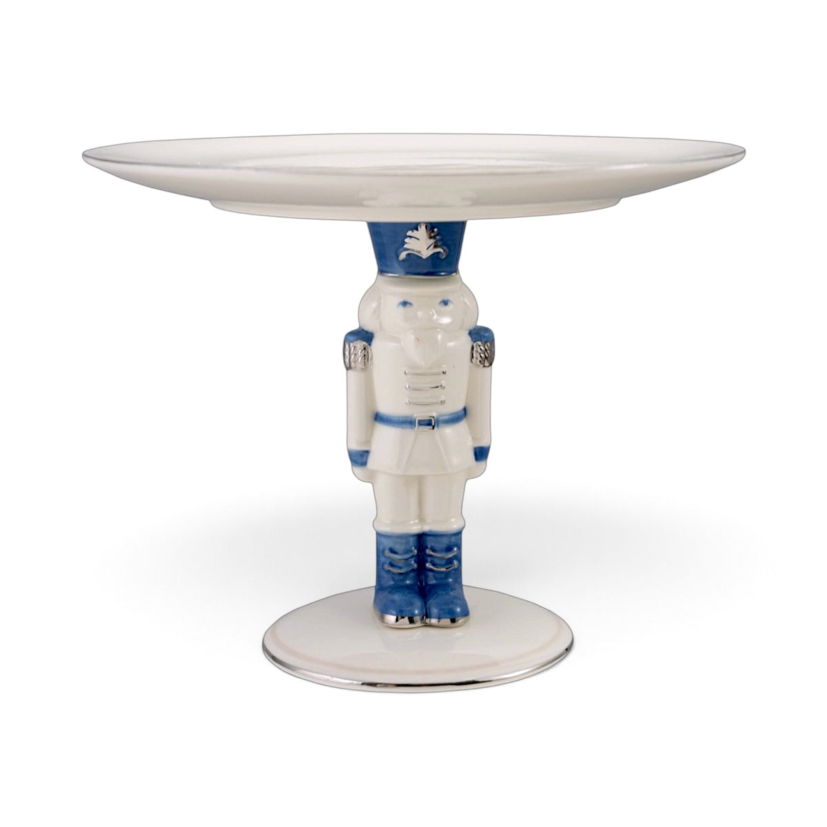 White ceramic pedestal with a blue and white nutcracker supporting a round tray, detailed with silver accents and a silver-edged base