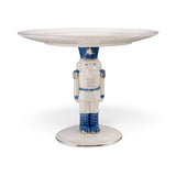 White ceramic pedestal with a blue and white nutcracker supporting a round tray, detailed with silver accents and a silver-edged base