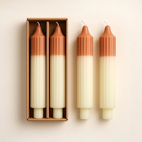 Set of two unscented, two-tone pleated taper candles in camel and mint, displayed with packaging.