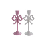 Two cast iron taper candle holders with bow design, pink and white