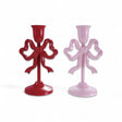 Two cast iron taper candle holders with bow design, red and pink