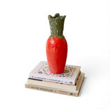 Orange ceramic carrot vase with green leaves