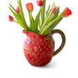 Red ceramic strawberry pitcher with green handle and leaf detailing