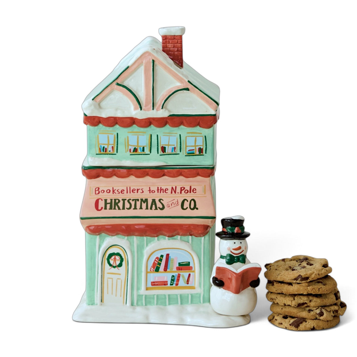 Hand-painted ceramic Christmas and Co. bookstore cookie jar with a mint green storefront, pink sign, red awnings, and snow-covered roof