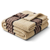 Cream faux sherpa throw blanket with black and grey stripes and a soft textured surface
