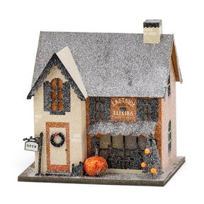 Eastside Elixirs lighted Halloween village house with glitter finish, pumpkins, storefront windows, and battery-powered interior light