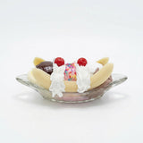 Realistic faux banana split with chocolate, vanilla and strawberry scoops in glass dish decor