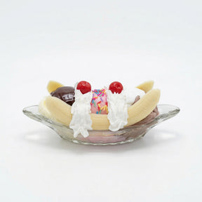 Realistic faux banana split with chocolate, vanilla and strawberry scoops in glass dish decor