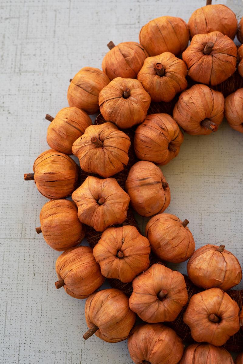 Textural orange faux pumpkins arranged in a fall wreath