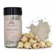 Finch + Fennel Kettle Corn Popcorn Seasoning in a clear jar with a black lid and pink label beside seasoned popcorn