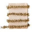 Slender gold glitter faux boxwood garland with small leaves, arranged in loose rows across an ivory background.