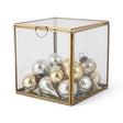 Small cube-shaped glass display box with a gold-tone metal frame and hinged glass lid