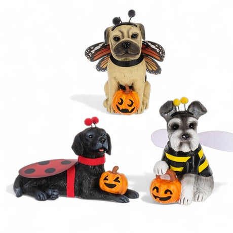 Three Halloween dog figurines in butterfly, ladybug, and bumblebee costumes, each holding a jack-o'-lantern.