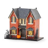 Madame Mystic lighted Halloween village house with orange glitter exterior, glowing windows, pumpkin, fencing, and 8-hour timer