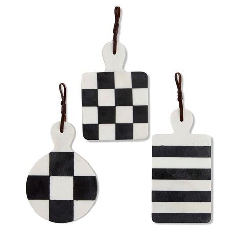 Black and white marble paddle boards with checkered or striped patterns, each featuring a leather hanging strap by Mud Pie