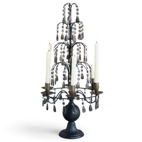 Tall matte black metal candelabra with tiered smoky acrylic crystal drops, six taper holders, and a sculpted pedestal base
