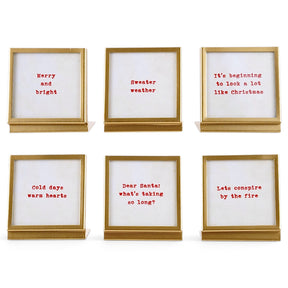 Six square gold metal and glass easel frames with red seasonal sayings on cream backgrounds.