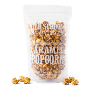 Old School Brand Caramel Popcorn in a clear 9-ounce resealable bag beside a glass bowl of golden caramel-coated popcorn