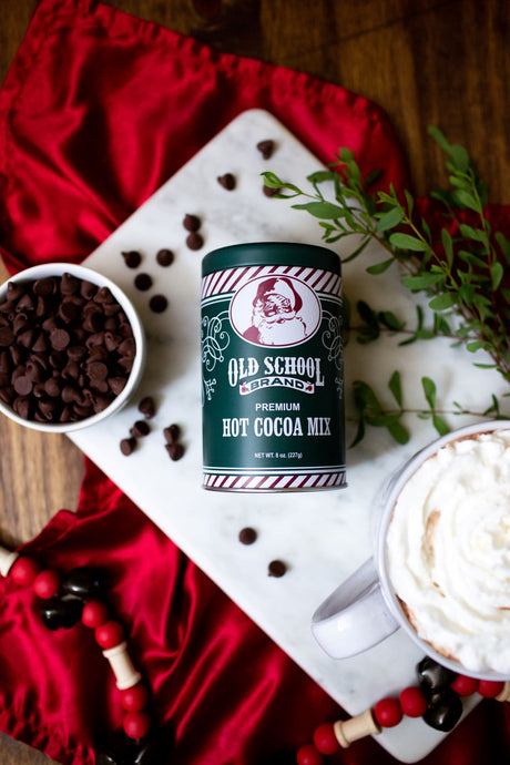 Old School Brand Premium Hot Cocoa Mix tin with chocolate chips and whipped cocoa on holiday table