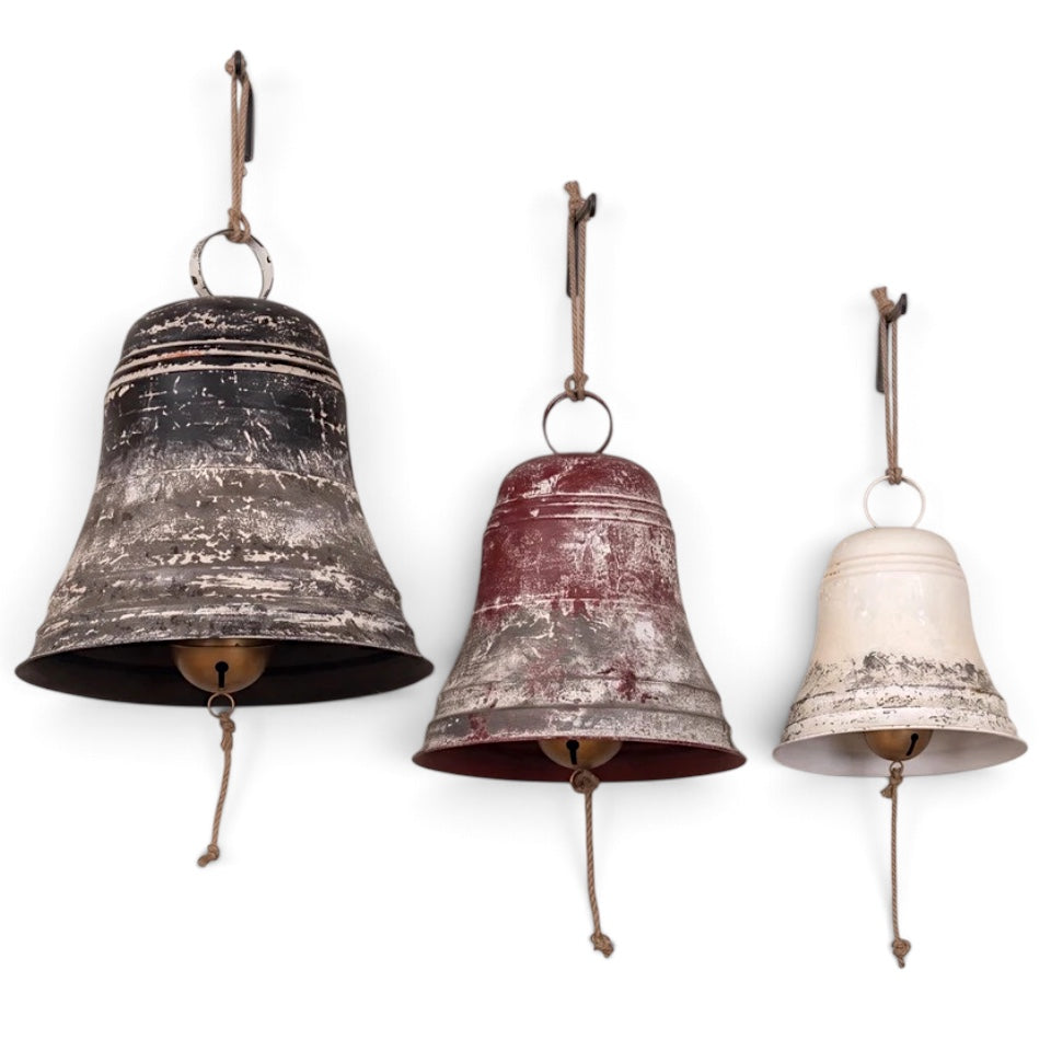 Oversized aged metal Christmas bells with rope hangers in three graduated sizes.