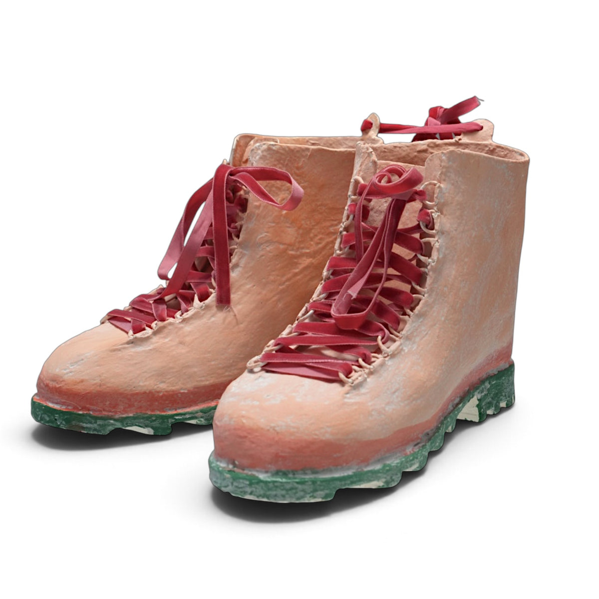 Pair of distressed pink decorative hiking boots with red velvet ribbon laces, red trim, and green treaded soles