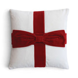 White square cotton velvet pillow with crossed red bands and an oversized dimensional red bow resembling a wrapped gift