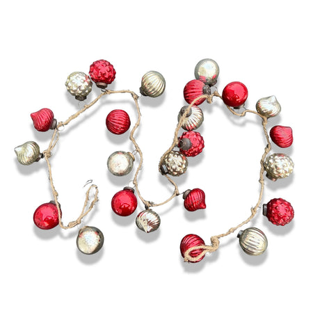 A garland of red and silver embossed glass ornaments with bronze toppers, tied with jute.
