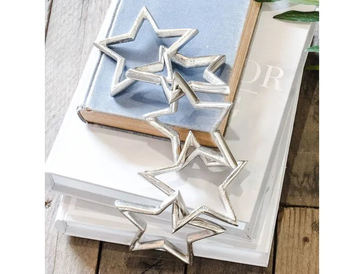 Silver aluminum star cut-out chain garland draped over stacked books on wooden surface