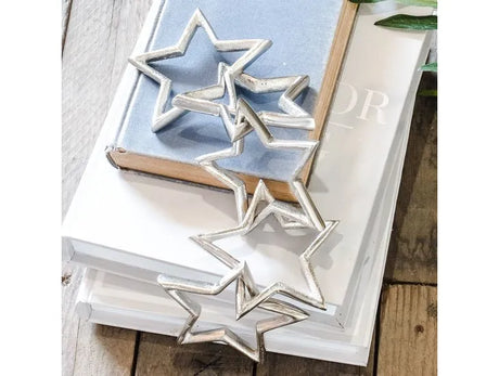 Silver aluminum star cut-out chain garland draped over stacked books on wooden surface