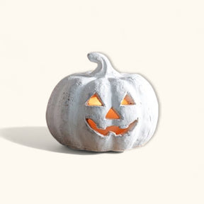 Small white terracotta jack-o’-lantern pumpkin with carved face and distressed finish