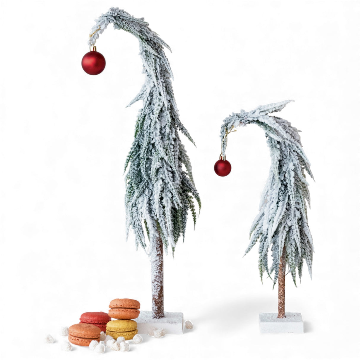 Snow-frosted faux evergreen trees with red ornaments on square bases