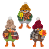 Three fall bird figurines in knit hats and scarves, each holding autumn accessories