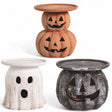 Three terracotta Halloween candle holders in pumpkin, ghost, and black jack-o'-lantern designs, each with a flat top for candles.