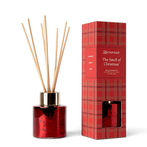 The Smell of Christmas mini reed diffuser in a red metallic glass bottle with a gold-tone collar, natural reeds, and red plaid gift box