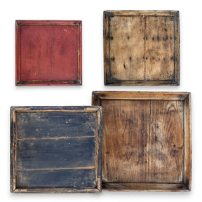 Assorted vintage hand-carved square wood trays with worn finish and natural grain