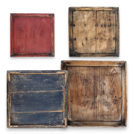 Assorted vintage hand-carved square wood trays with worn finish and natural grain