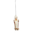 Vintage reproduction child skiing ornament in a cream hooded outfit with red mittens, a golden bow, skis, and brown ski poles