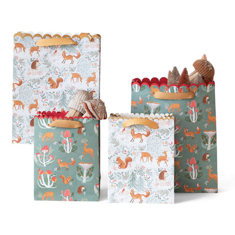 Two printed recycled paper gift bags with woodland animal and botanical designs, scalloped trim, and satin handles.